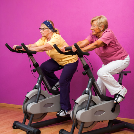 Portrait of two senior ladies at spinning session in health club.の写真素材