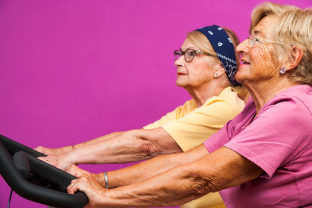 Portrait of two fit Senoir women working out on bicycles in health club.の写真素材
