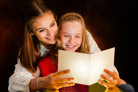 Close up portrait of young Woman reading Christmas card to youngster.の写真素材