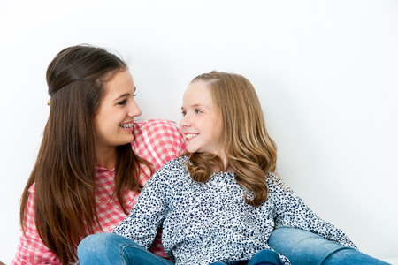 Close up Portrait of two young sisters looking at each other.Isolated on white background.の写真素材