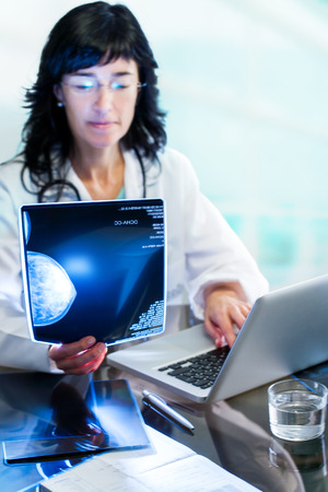 Close up portrait of Female doctor analyzing x-ray mammogram at desk in clinic.の写真素材
