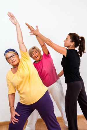 Female aerobic instructor helping senior ladies in fitness session.の写真素材