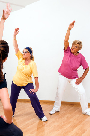 Two Senior woman doing fitness session in health club with instructor.の写真素材