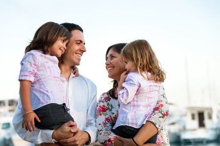 Close up family portrait of young couple holding their kids in arms outdoors.の写真素材