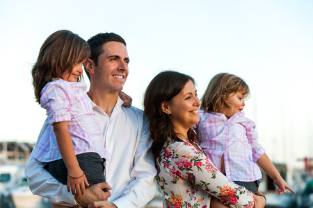 Close up portrait of young family with two little daughters looking into the distance at sunset.の写真素材