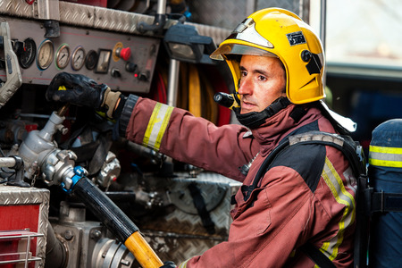 Fireman controlling water pressure at back of fire truck.の写真素材