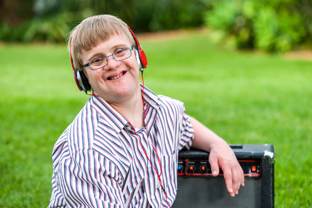 Close up portrait of young man with down syndrome wearing headphones outdoors.の写真素材