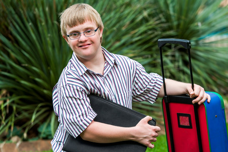 Close up portrait of young Down syndrome student with file and trolley.の写真素材