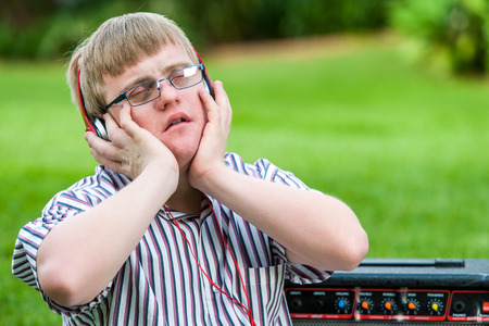 Close up portrait of handicapped boy enjoying music on head phones outdoors.の写真素材