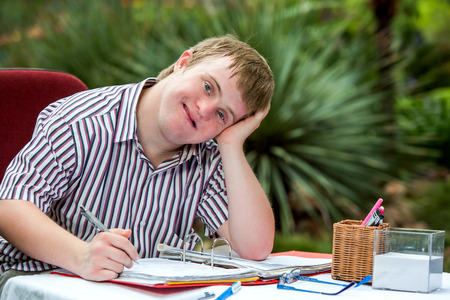 Close up portrait of Handicapped student resting on hand at desk in garden.の写真素材