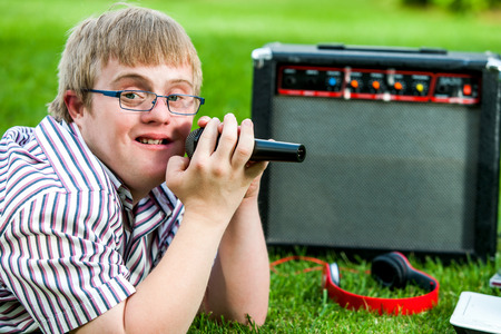 Close up portrait of handicapped boy singing with microphone and amplifier outdoors.の写真素材