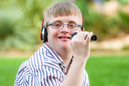 Close up portrait of young handicapped man singing with microphone outdoors.の写真素材