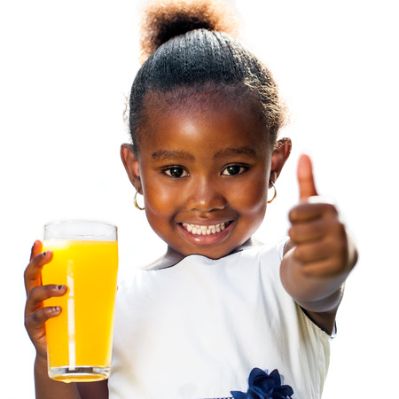 Portrait of cute little African girl doing thumbs up holding orange juice.Isolated on white background.の写真素材