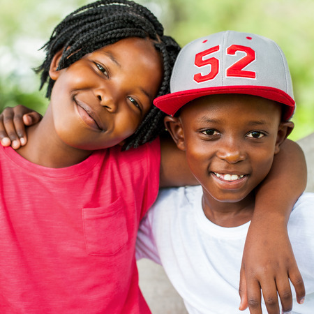 Close up face shot of smiling African boy and girl outdoors.の写真素材