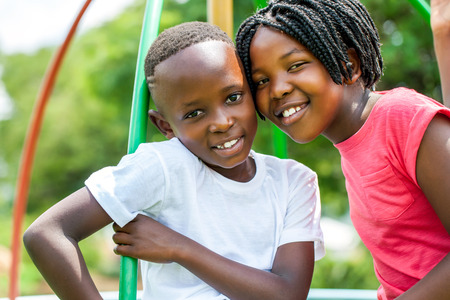 Close up face shot portrait of African kids joining heads in park.の写真素材