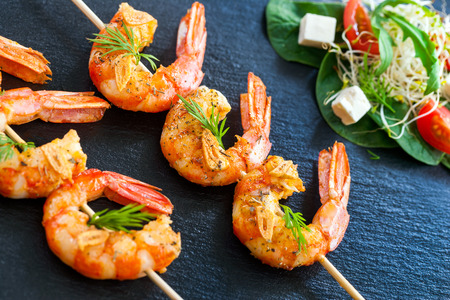 Extreme close up of grilled queen prawn brochettes spiced with natural herbs.の写真素材