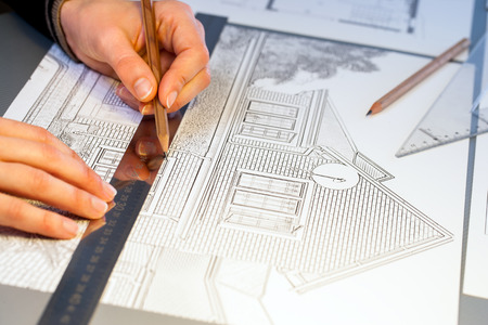 Extreme close up of human hands working on house plan project with pen and ruler.の写真素材