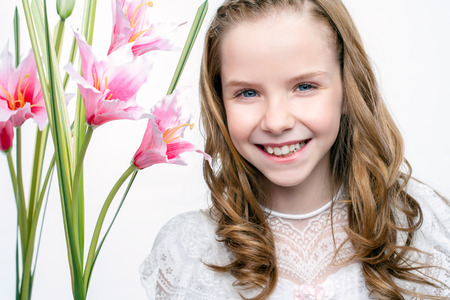 Close up studio beauty portrait of cute communion girl with flowers.の写真素材