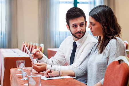 Portrait of young business couple reviewing work in conference room at Hotel.の写真素材