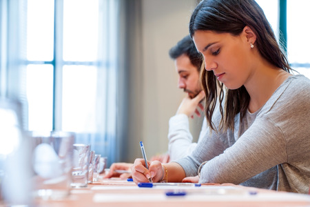Portrait of young students at work in Hotel conference room. Young woman writing with pen at desk.の写真素材