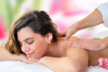 Close up of young attractive woman enjoying back massage. Therapist hands massaging shoulders and neck.の写真素材