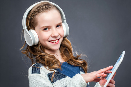 Close up portrait of cute girl wearing headphones listening music on digital tablet.の写真素材