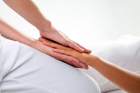 Close up of chiropractor doing reiki treatment on girls hand.の写真素材