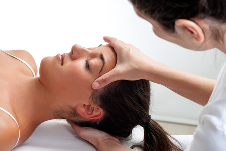 Close up of osteopath doing healing treatment on womans head. Hands doing massage on front and back of head.の写真素材