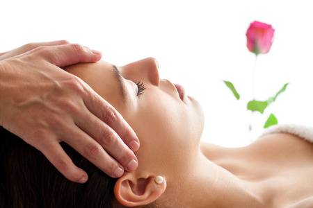 Close up portrait of Woman having Facial massage. Therapist massaging womanâs head isolated against white background.の写真素材