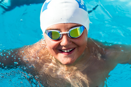 Close up portrait of teenager with swim cap and goggles in swimming pool.の写真素材