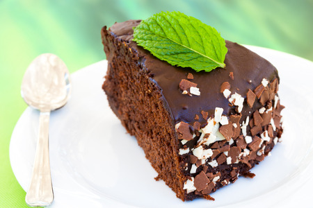 Macro close up of dark chocolate cake with mint leaf.の写真素材