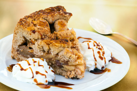 Macro close up portion of cinnamon apple pie with whipped  cream and caramel.の写真素材