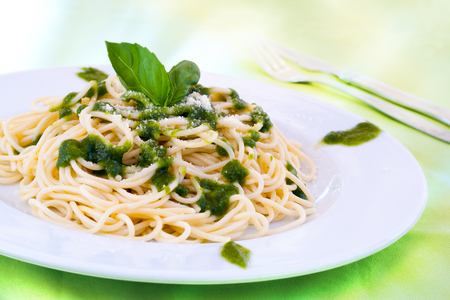 Close up of traditional Italian spaghetti with green pesto sauce and parmesan cheese.の写真素材