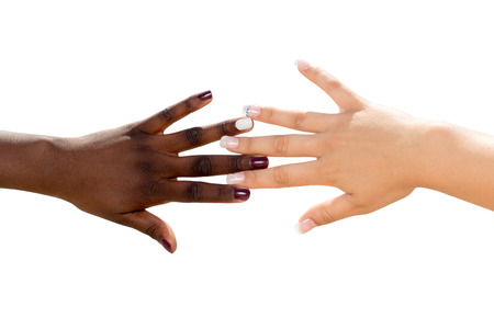 Macro close up of african female hand touching white female hand.Two diverse nail polished hands isolated on white background.の写真素材