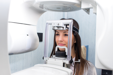 Close up head shot of girl taking dental tac with cephalometric panorama x-ray machine in clinic.の写真素材