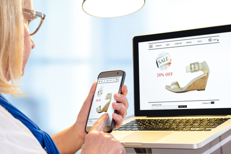 Close up portrait of senior woman doing online shopping with smart phone and laptop.の写真素材