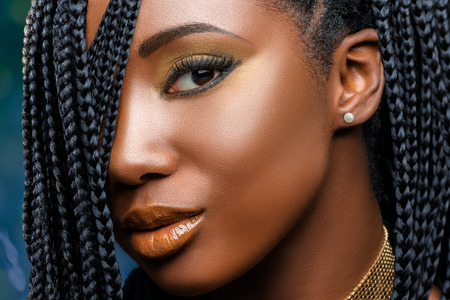 Extreme close up facial beauty portrait of  young charming african girl with braided hairstyle.Studio shot of woman with professional make up looking at camera.の写真素材