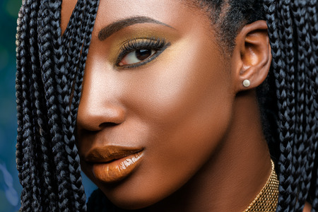 Extreme close up facial beauty portrait of  young charming african girl with braided hairstyle.Studio shot of woman with professional make up looking at camera.の素材 [FY31081161379]