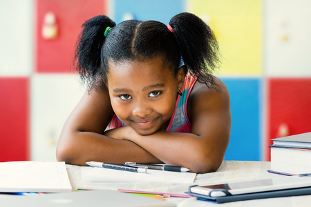 Close up portrait of little african student resting with head on arms in classroom.Girl showing bored facial expression.の写真素材