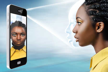 Smart phone projecting light bean on african female face.Side view of conceptual face recognition technology.の写真素材