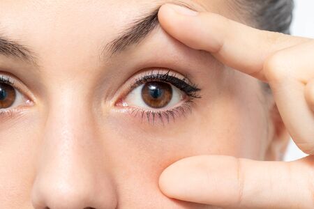 Macro detail of woman opening eye with fingers.の写真素材