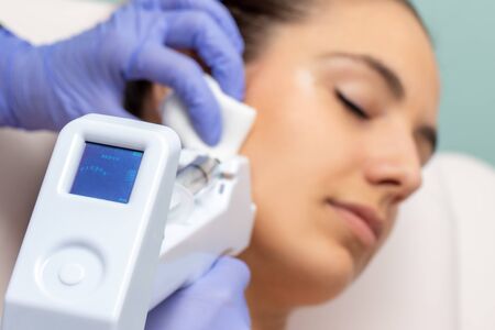 Micro needling technology used on young woman. Device with digital screen indicating depth applied on skin.の写真素材