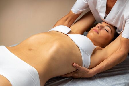 Close up of physiotherapist doing shoulder blade therapy on young female patient.Woman laying on spa bed with therapist manipulating spinal ligaments.の写真素材