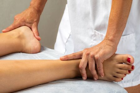 Physiotherapist doing manipulative treatment on female feet.の写真素材