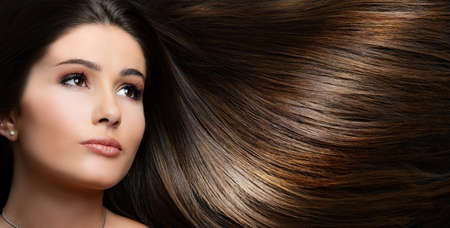 Glamour beauty portrait of stunning brunette with long stylish brown shiny hair on side of head.の写真素材