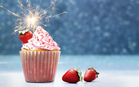 3D illustration of strawberry flavored cupcake with festive fire spark against blue background.の写真素材