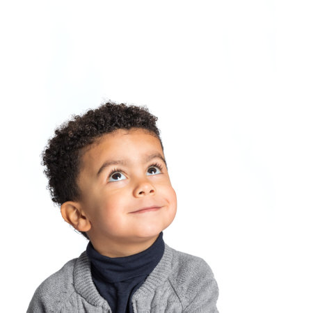 Close up studio portrait of cute little afro american boy looking up. Isolated on white background.の写真素材