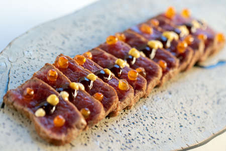 Macro close up of appetizing wagyu beef sirloin tataki. Multiple slices of crisp and reddish meat...