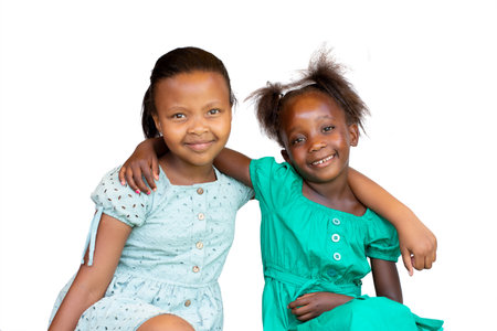 Close-up Studio portrait of two young African kids sitting together. Isolated on white background.の写真素材