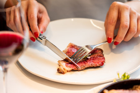 Close up detail of female hands  cutting sirloin steak in gourmet restaurant.の写真素材